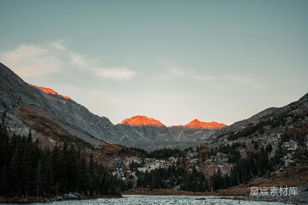 高清摄影 一座被山环绕的湖泊，前景处有树木。