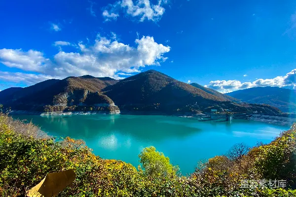 高清摄影 白天湖周围被绿树和群山环绕，在蓝天之下。