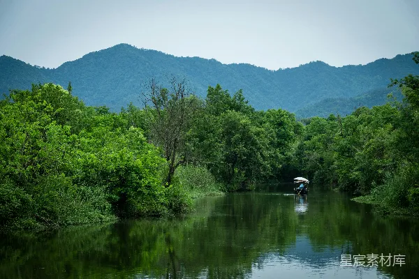 高清摄影 河岸边一艘船上的人，背景是山峦。