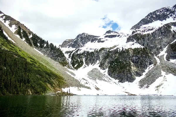 高清摄影 一片宁静的湖水，周围环绕着皑皑白雪覆盖的山峦和葱郁的森林。