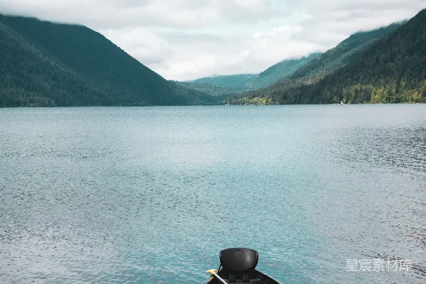 高清摄影 湖边一艘小船，背景是群山。