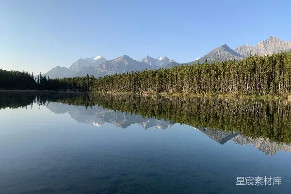 高清摄影 一个被森林环绕的湖泊，背景是山脉。