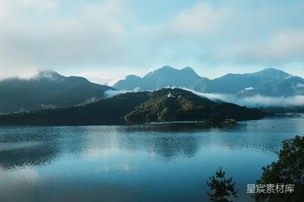 高清摄影 平静的湖泊映照着云雾缭绕的山峦，在一片阴天的背景下。
