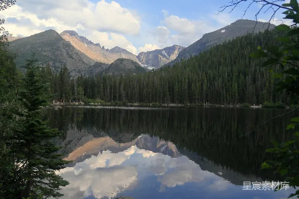 高清摄影 一片被树木和山峦环绕的湖，在阴云密布的天空下。