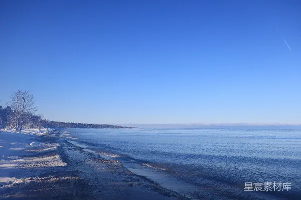 高清摄影 一段雪覆盖的海滩绵延至一个水域旁边