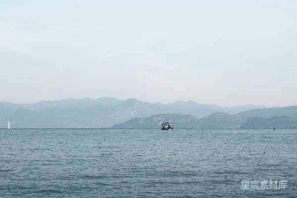 高清摄影 一艘船在平静的湖面上航行，远处有山峦。