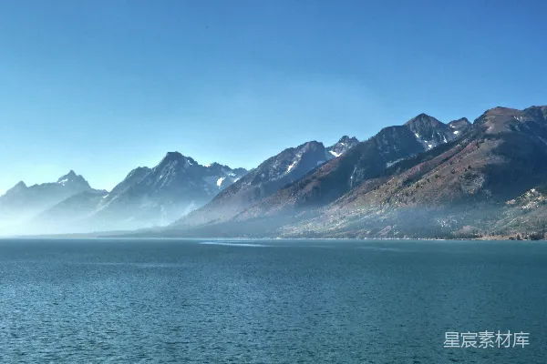 高清摄影 白天，蓝海上方覆盖着白雪的山峰，蓝天背景下。