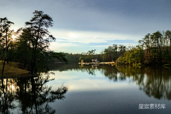 高清摄影 一片被树木环绕的水域，天空中有云朵。