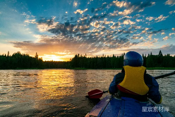 高清摄影 湖面上一艘 kayak 上的人，周围有树木和夕阳的景象