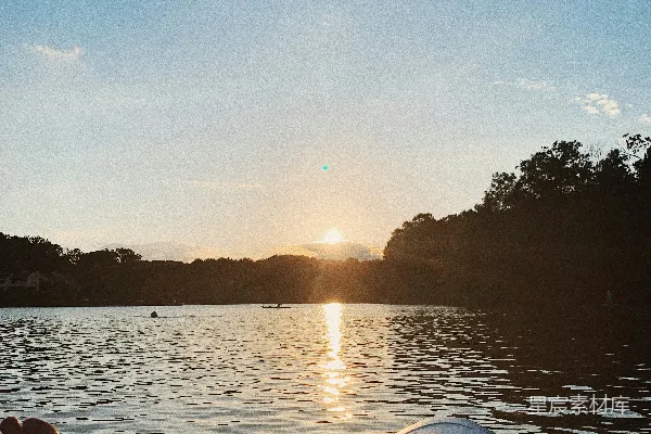 高清摄影 身穿蓝色和白色夹克的人在湖上乘坐独木舟，夕阳西下时