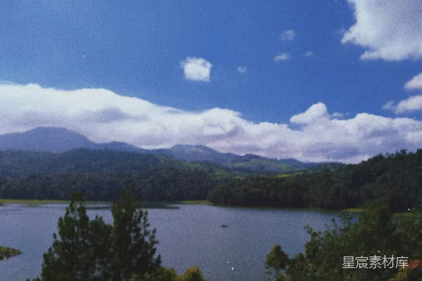 高清摄影 一片被树木和山峦环绕的湖泊，在蓝天之下。