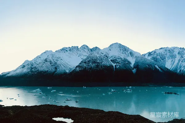 高清摄影 白天山顶附近有一片积雪的山体靠近水域