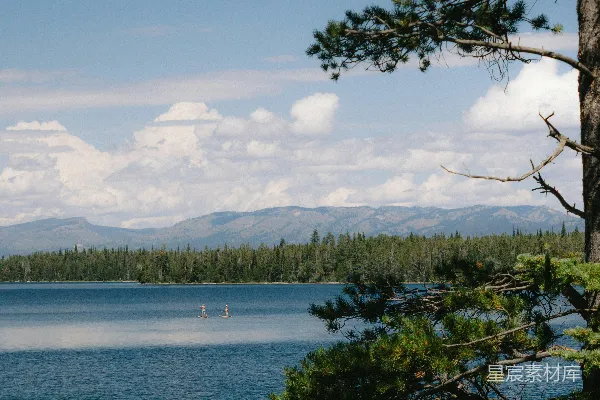 高清摄影 一片被树木环绕的湖泊，背景是群山。