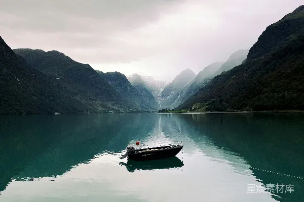 高清摄影 小船停泊在一片宁静的碧蓝色湖泊旁，周围是连绵的山峦。