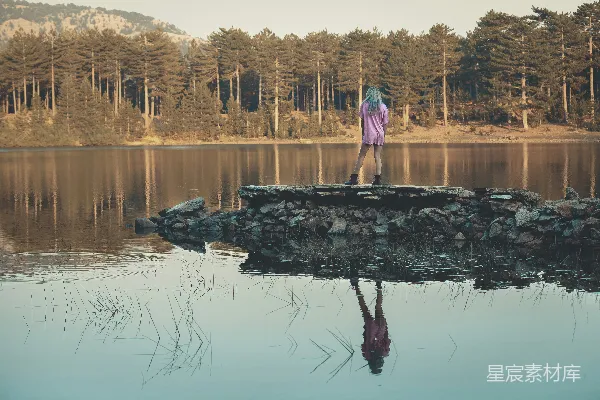 高清摄影 粉色长袖上衣的女人站在湖边的岩石上，在白天拍摄。