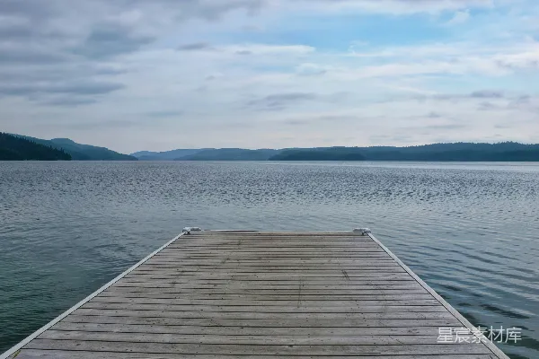 高清摄影 木质码头伸入一片平静的湖边，天空有云。