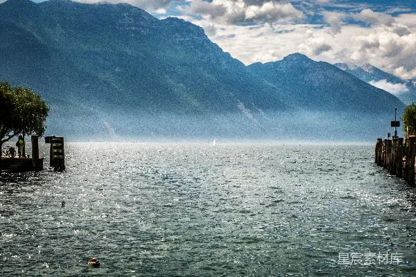高清摄影 模糊的湖景，远处连绵的山峦和阴云密布的天空。
