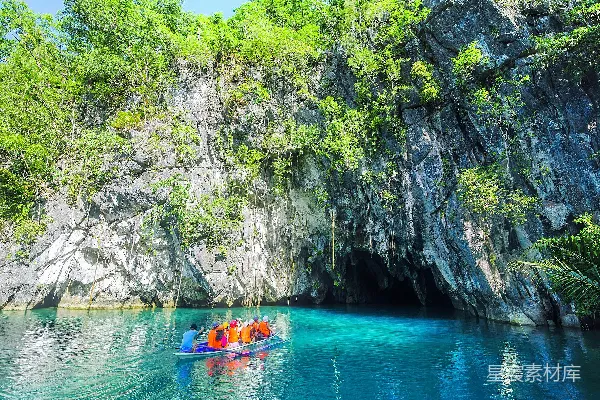 高清摄影 一群人在一艘船上，在悬崖旁的水域中，背景是Puerto Princesa Subterranean River国家公园。