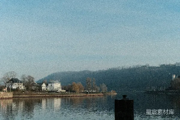 高清摄影 河岸有建筑和树木的平静河流。