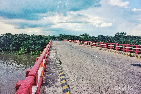 高清摄影 白天河边红色和白色道路两侧白云下