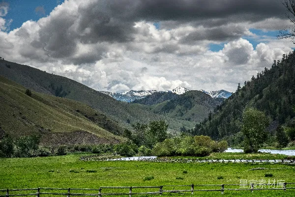 高清摄影 白天绿草地上方有绿山和白云的近景中