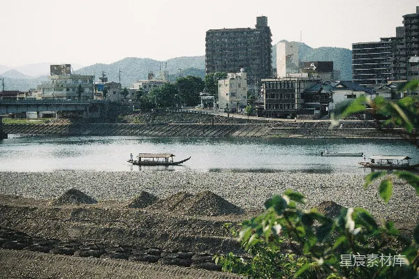高清摄影 一条河里有一条船，背景中有城市。