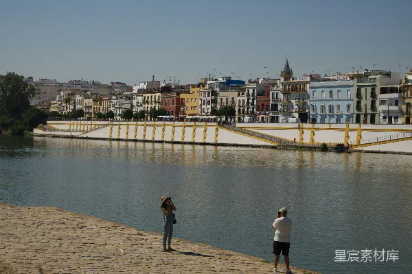 高清摄影 河边的两个人与色彩斑斓的城市建筑。