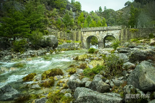 高清摄影 河边一座桥横跨一条围绕着岩石的河流
