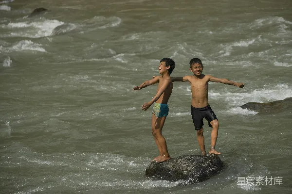 高清摄影 两个男孩站在海滩的岩石上