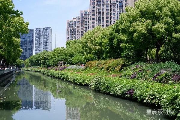高清摄影 一条运河流过绿树与现代建筑之间。