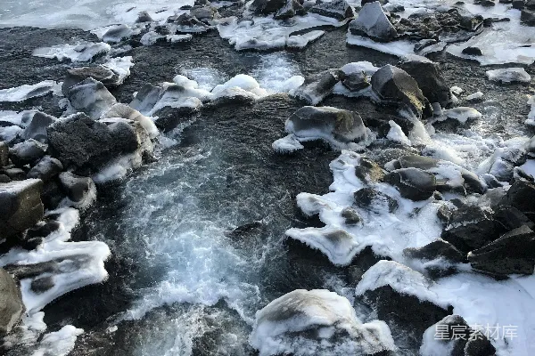 高清摄影 一条水流 surrounded 由冰雪覆盖的岩石环绕