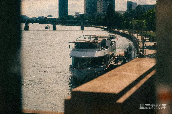 高清摄影 白船停靠在河边，城 skyline和桥在旁。