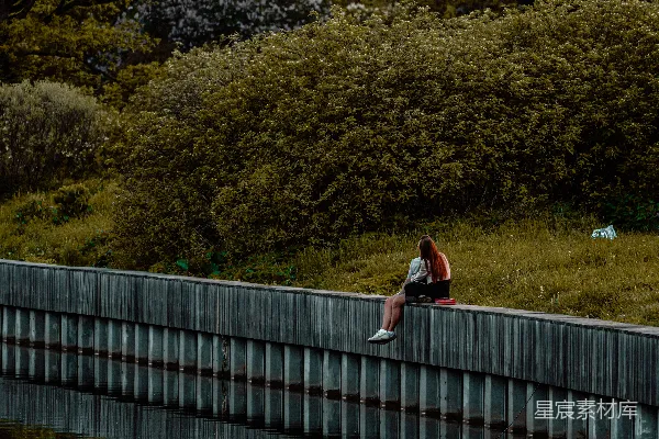 高清摄影 一个人坐在水边，映照在水面中。