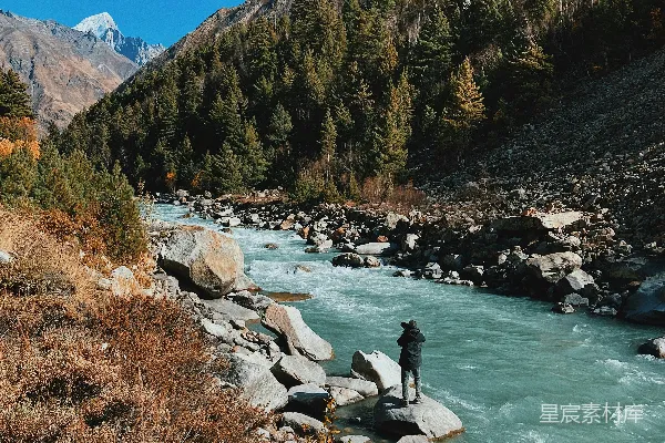 高清摄影 蓝天白云下，夹在绿山与褐山之间的河流在白天流淌。