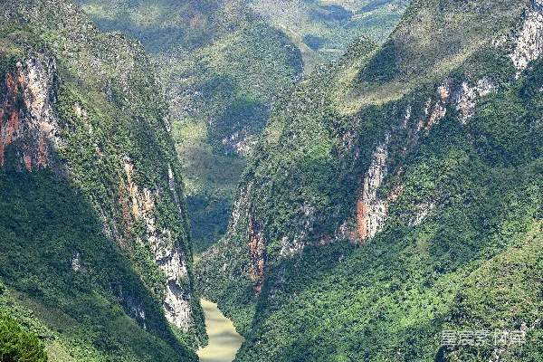 高清摄影 一条宽广的河流流经一片翠绿的山间谷地。