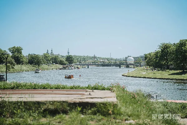 高清摄影 风景如画的河流上停着小船，一座桥梁横跨其上，远处是城市 skyline。