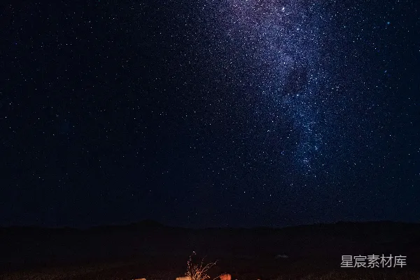 高清摄影 一群人在满天星辰闪烁的夜空中围坐在篝火旁。