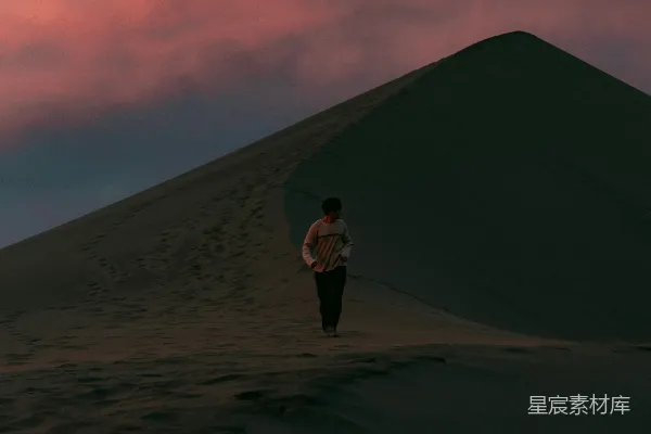 高清摄影 夕阳下男子在沙丘上行走。