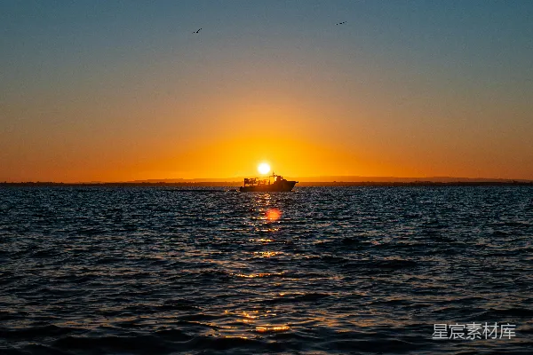 高清摄影 夕阳西下，海天相接处有一艘船隐约可见。