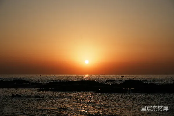高清摄影 夕阳西下，海平面上有岩石在 foreground。