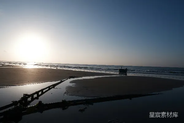 高清摄影 夕阳照亮一片沙滩、大海和一根黑色的管子。