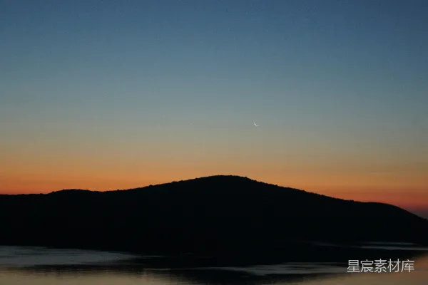 高清摄影 夕阳西下，一座山头和一片水域之间。