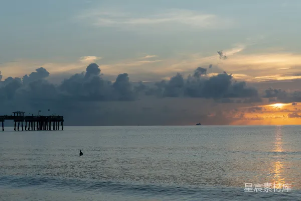 高清摄影 夕阳落下海平线远处有一座码头。