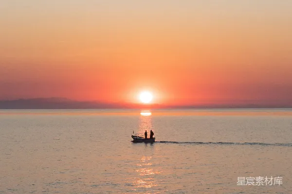 高清摄影 夕阳下两个人的轮廓在海面上划船的情景