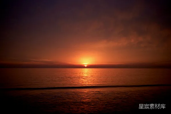 高清摄影 在阴云密布的一天里，夕阳正沉落在海面上。