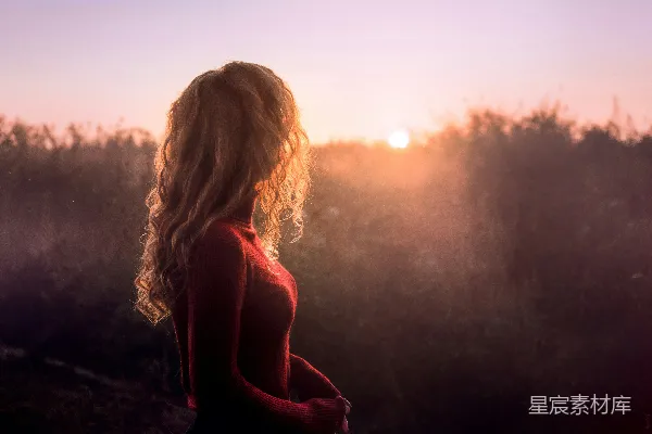 高清摄影 女人站在阳光下看着正处金时的太阳。