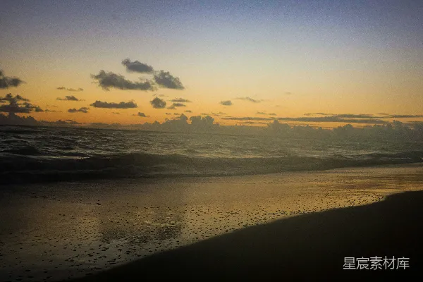 高清摄影 夕阳下的海滩，沙上倒映着水面的光芒。