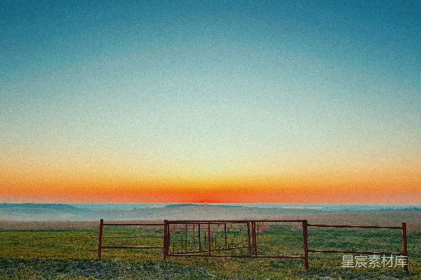 高清摄影 草地上一座红色的门楼，背景是夕阳。