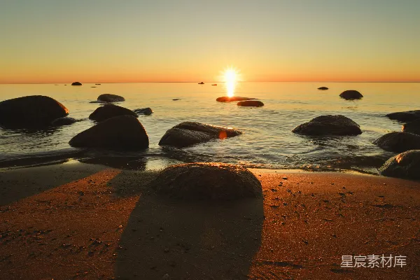 高清摄影 夕阳西下，海平面上岩石闪烁水波中。