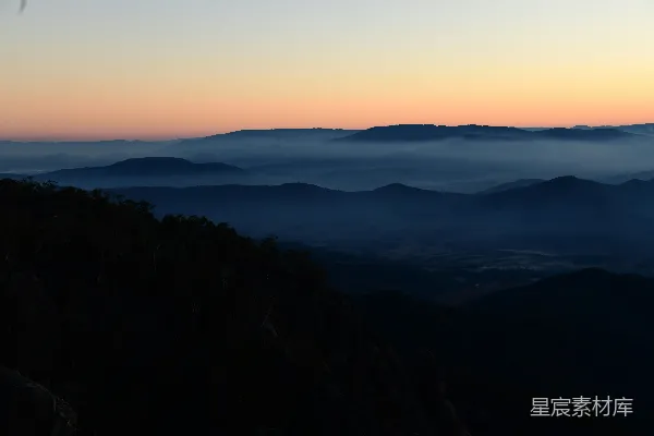 高清摄影 山脚下一只鸟飞过，背景是夕阳西下。